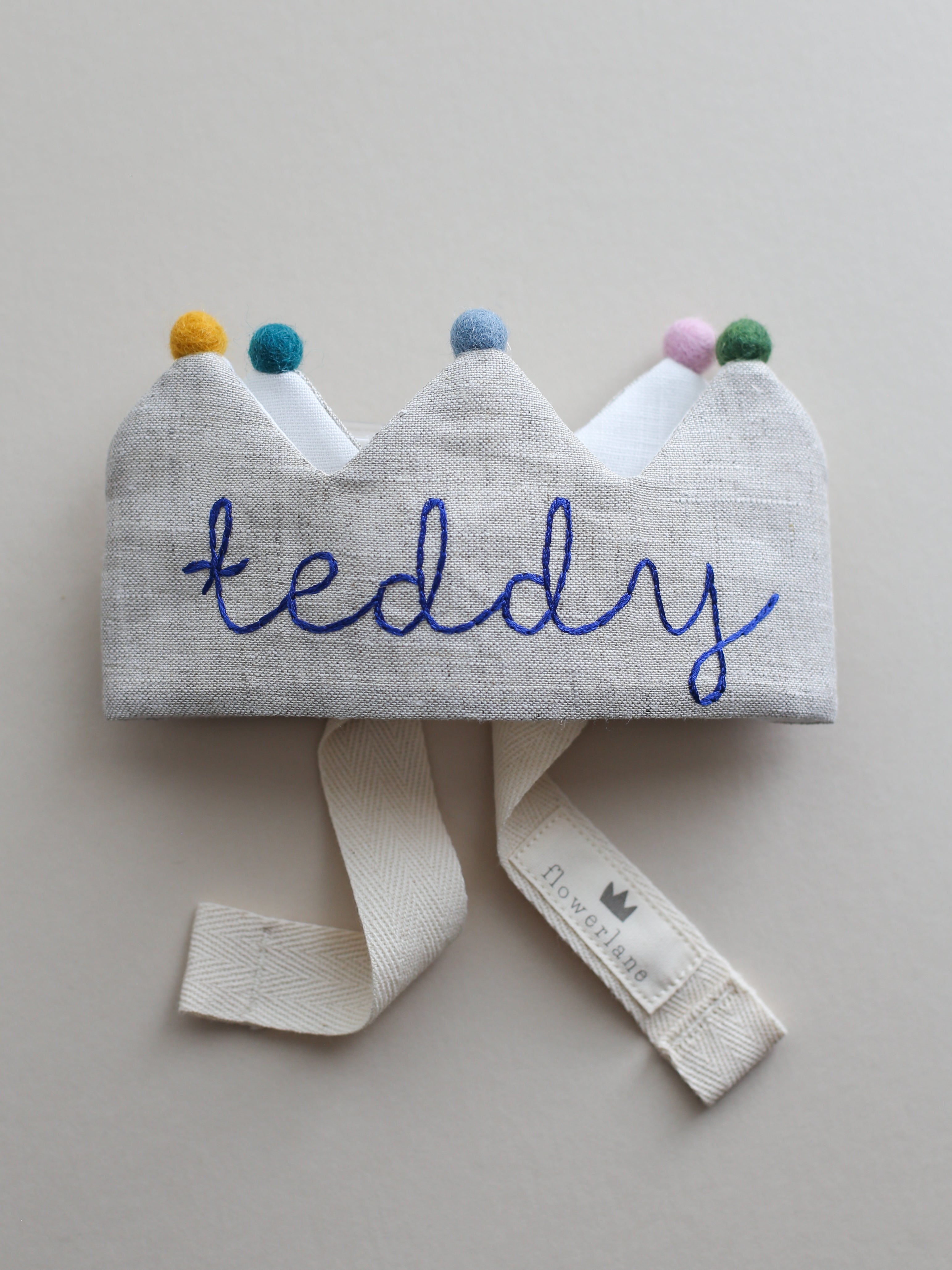 handmade embroidered birthday crown with blue thread and colorful pom poms