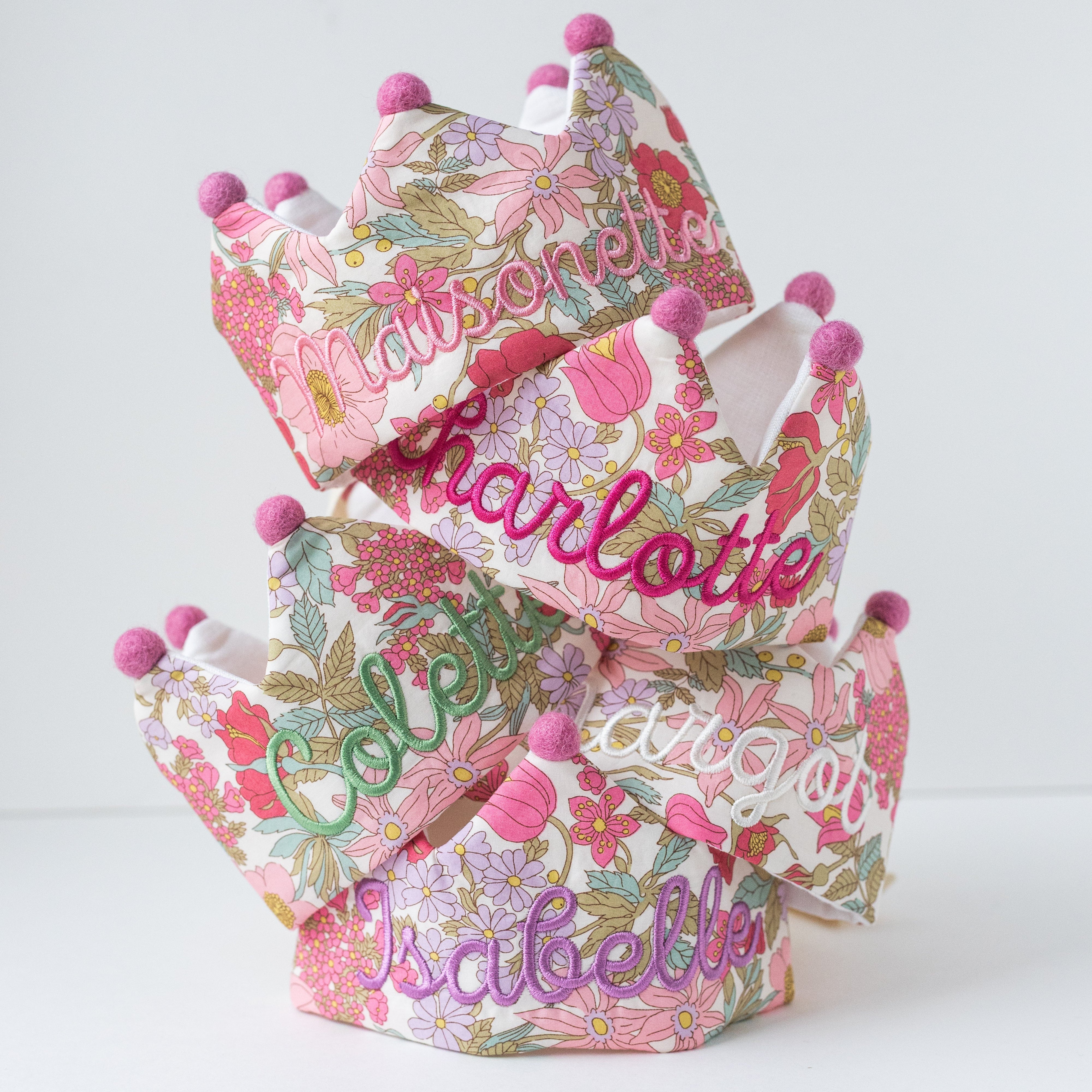 Floral-patterned crowns with embroidered names on a white background