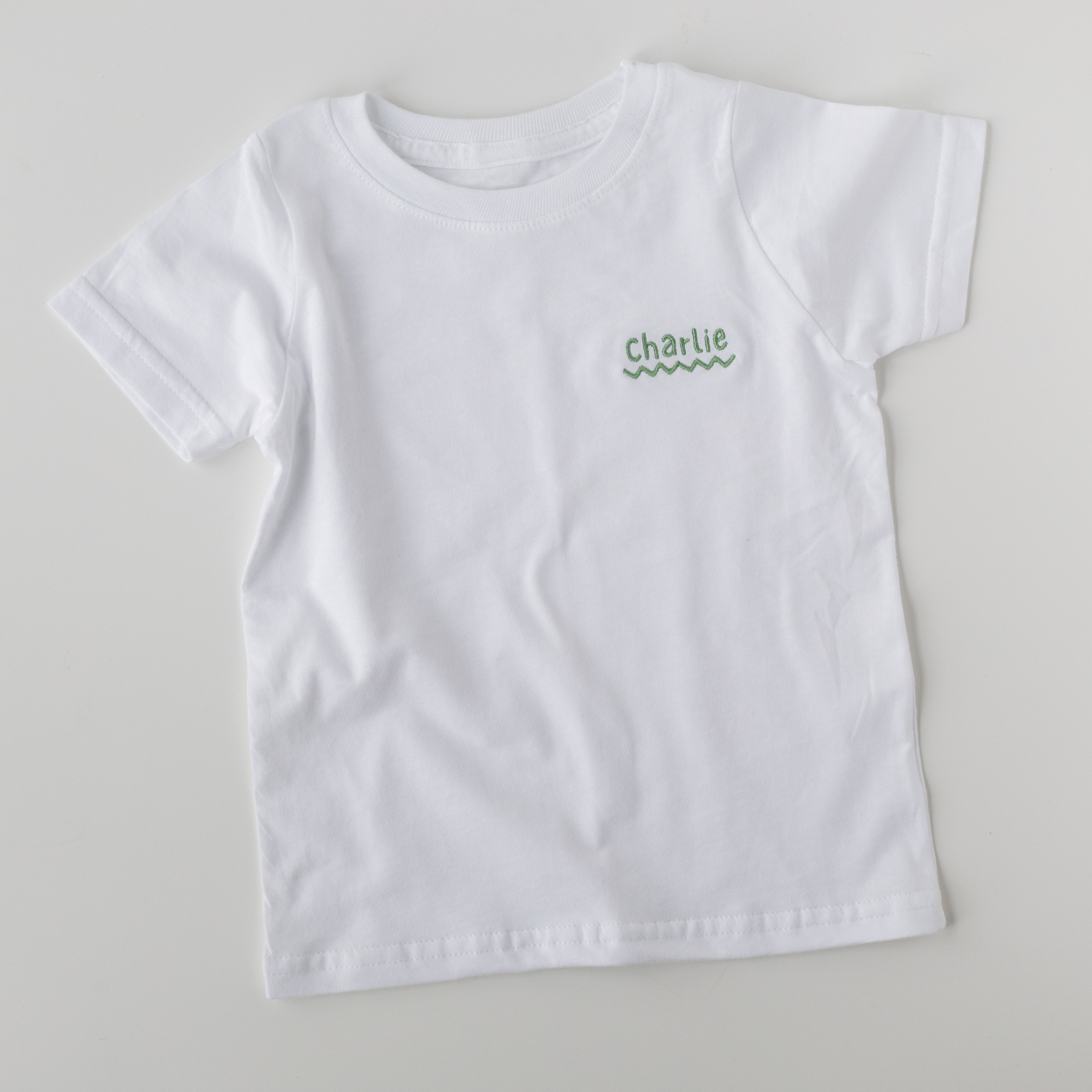 White t-shirt with 'Charlie' printed on a gray background