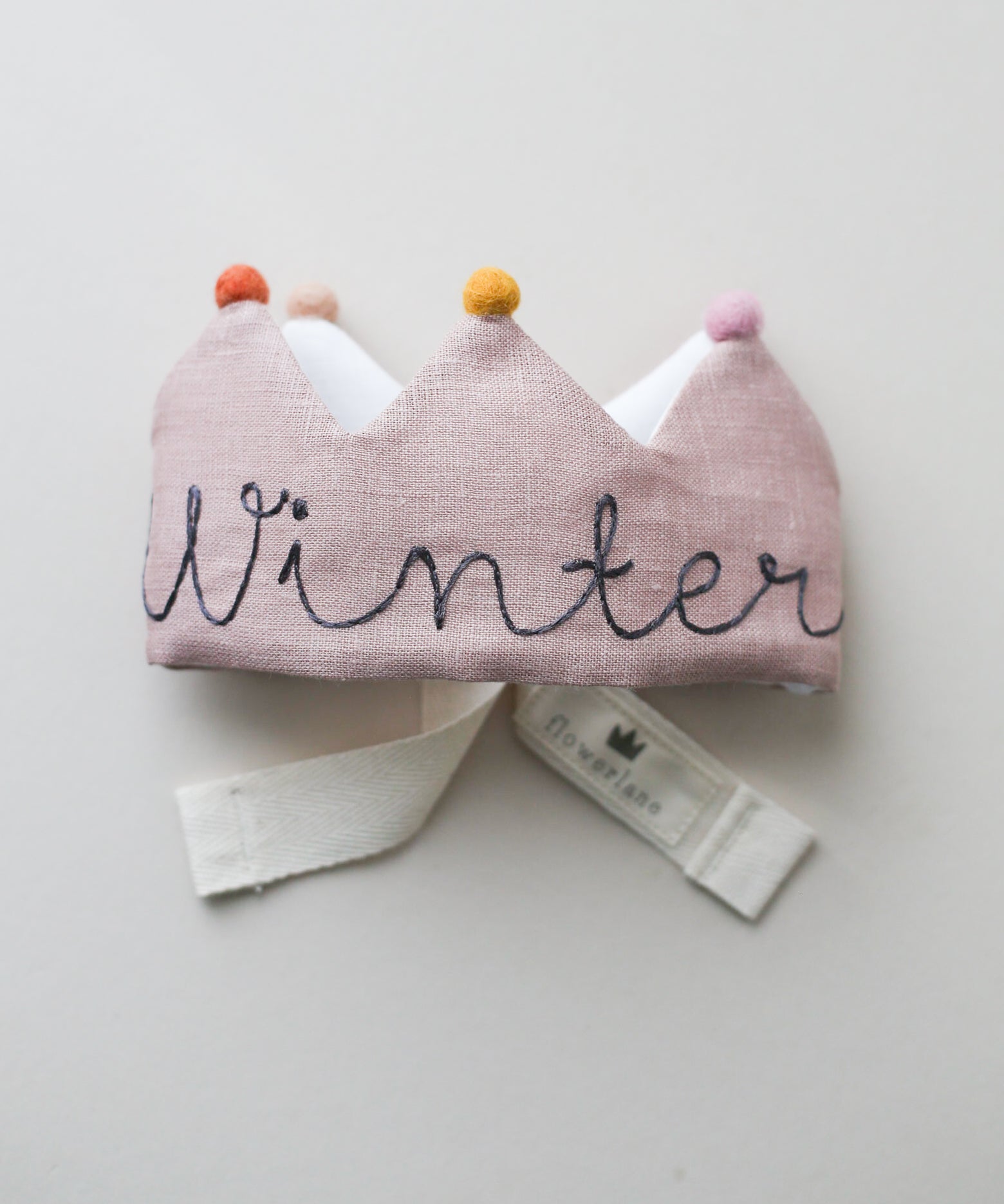 Handmade blush linen birthday crown with gray embroidery and felt pom poms