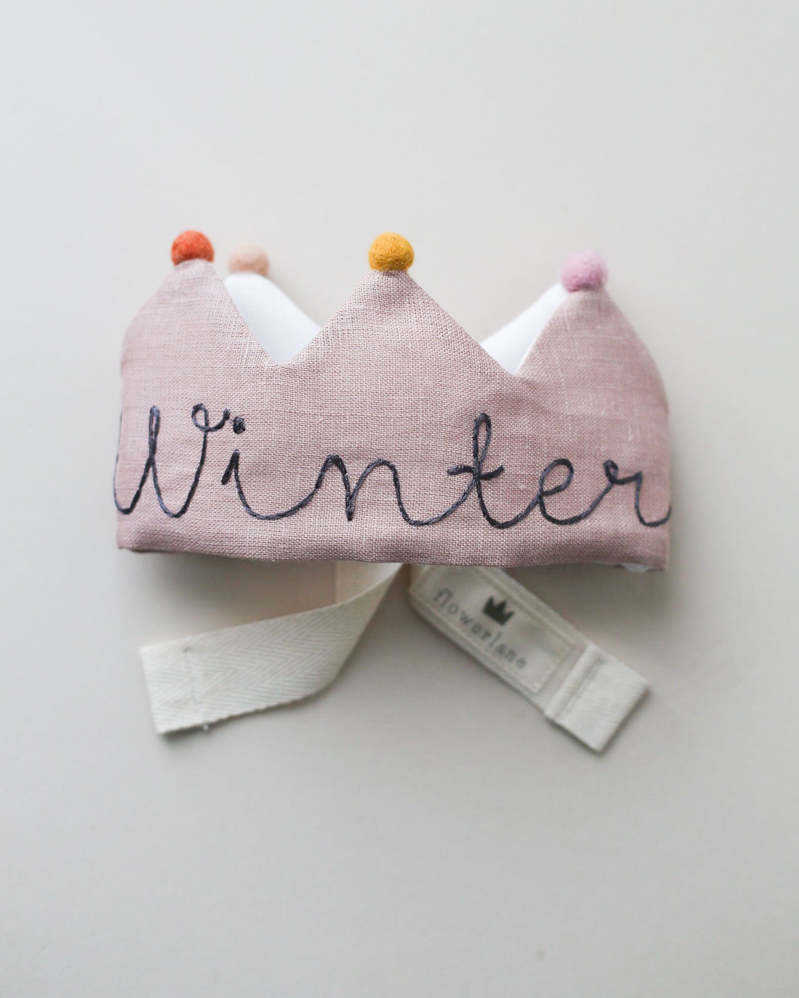 Handmade blush linen birthday crown with gray embroidery and felt pom poms