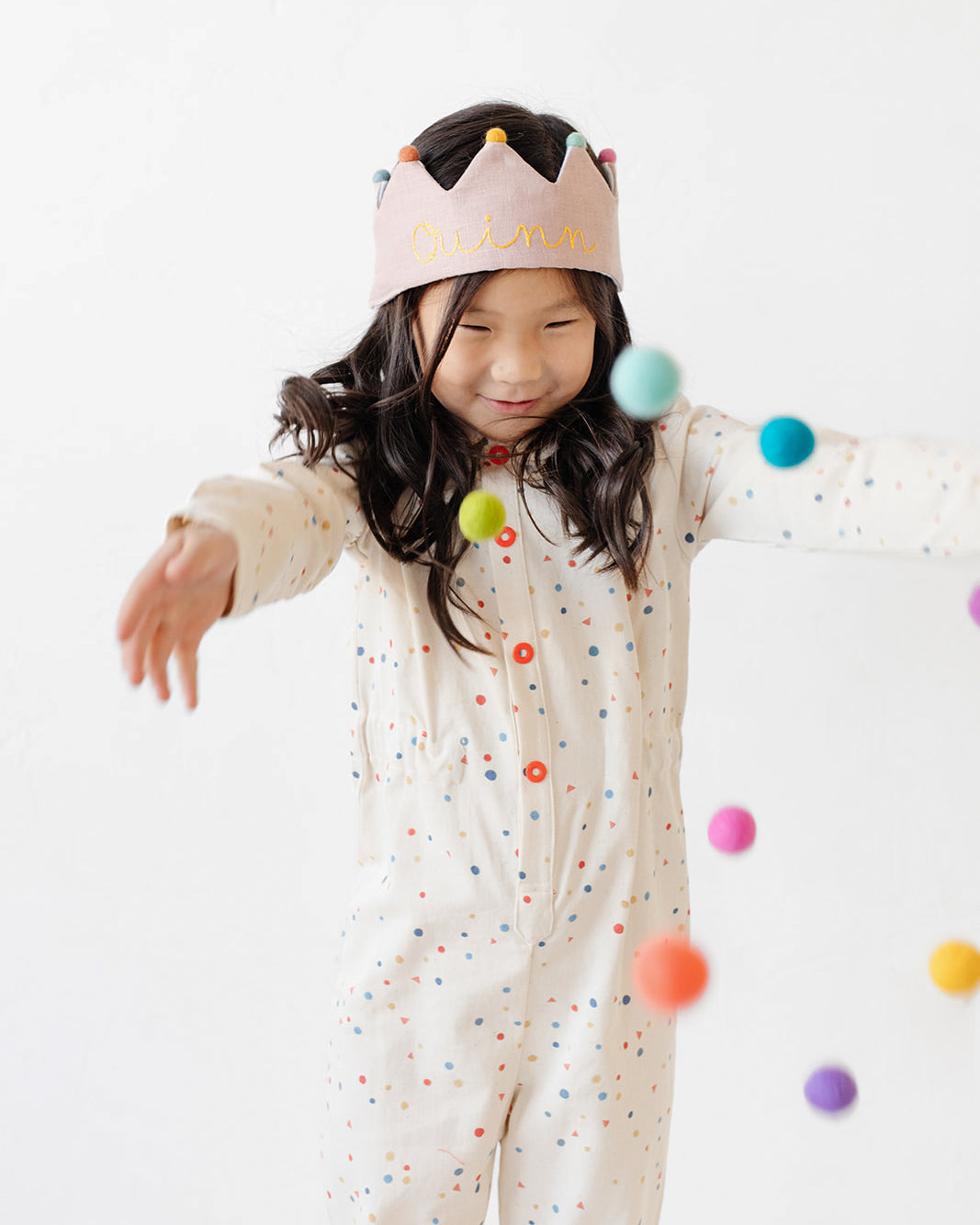 girl wearing polka dot romper with pink birthday crown