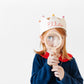 Girl wearing custom crown with name stitched holding a magnifying glass