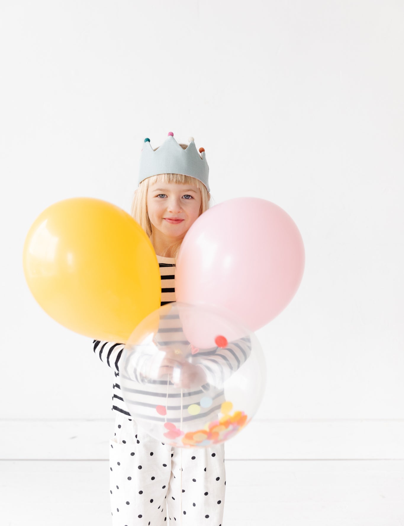 Girl with birthday crown and balloons.