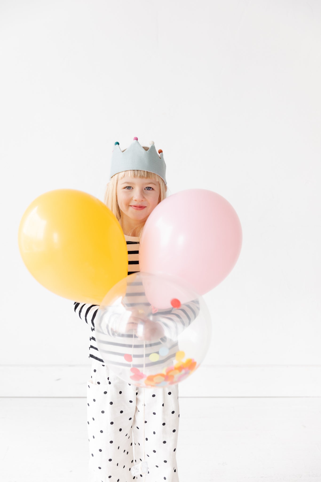 Girl with birthday crown and balloons.