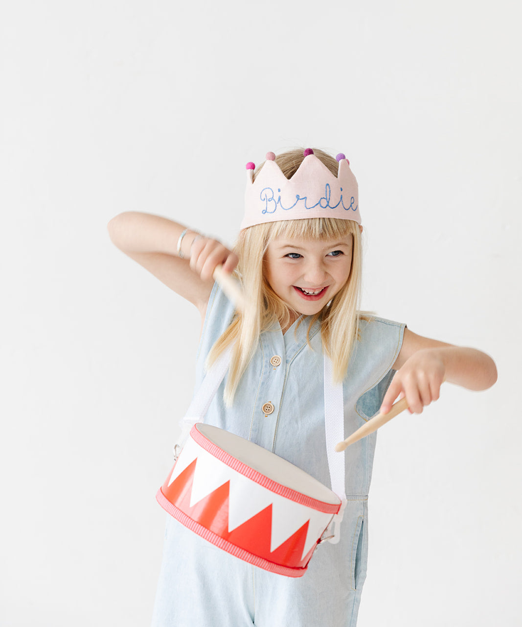 girl wearing pink birthday crown and playing drum